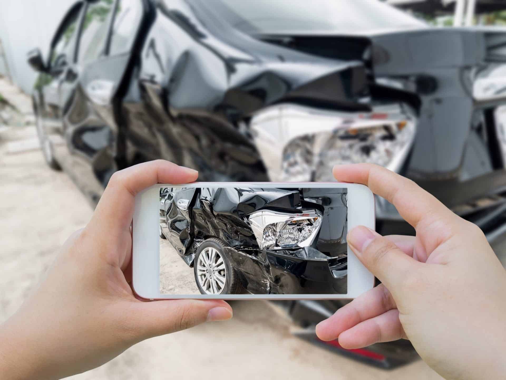 Man taking picture of damaged car after an car accident